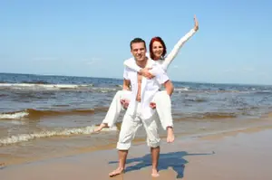 woman on the back of the man wearing all white at the beach