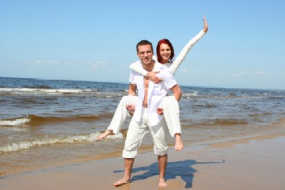 woman on the back of the man wearing all white at the beach