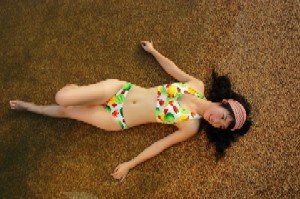 Asian girl in floral bikini laying flat on sand