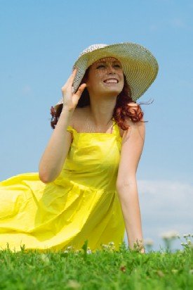 sun clothing lady in yellow dress and hat sitting on green lawn