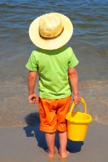 boy with sun protection hat facing the beach